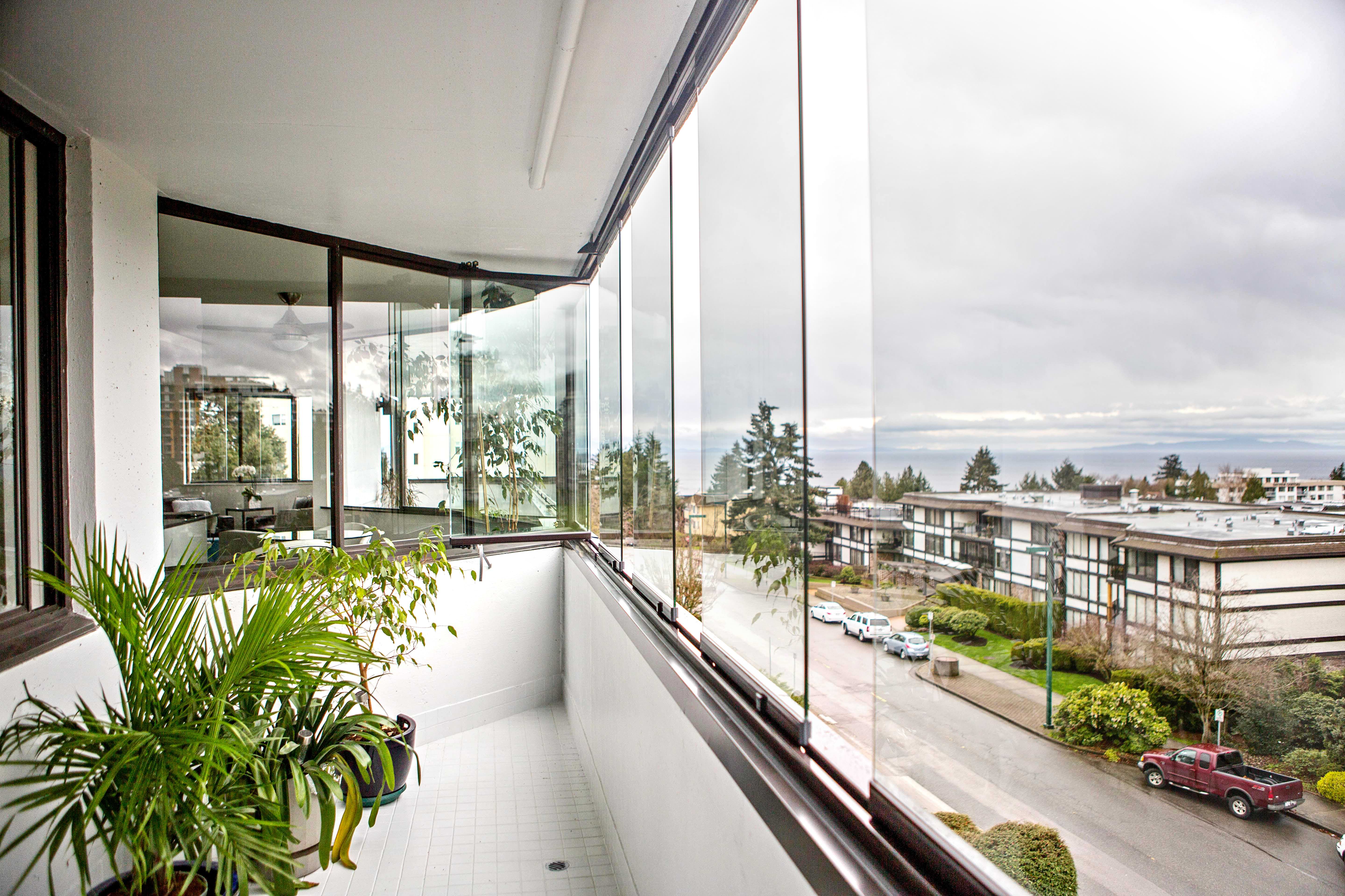 Vit balkong med inglasade fönster